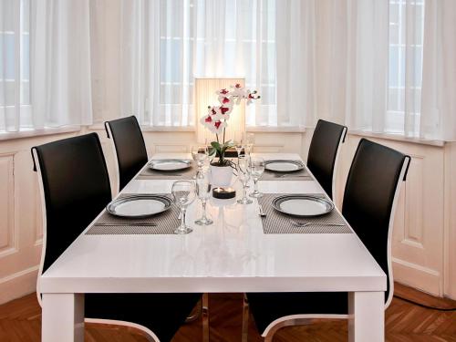 una mesa blanca con sillas negras y una mesa blanca con flores en Apartment Romantic Living by Interhome, en Viena