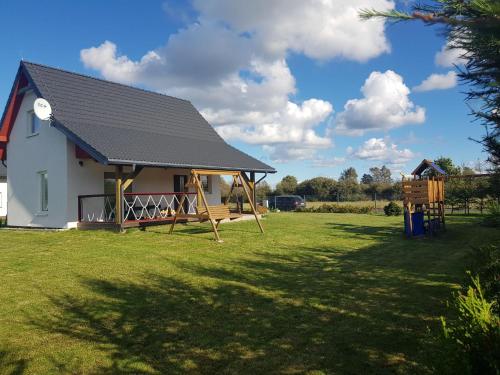 a house with a porch and a playground at Holiday Home Modrzewiowy Zakątek by Interhome in Smołdziński Las