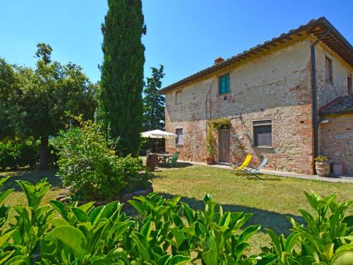 an old stone house with a chair and an umbrella at Apartment Podere La Torre-1 by Interhome in Certaldo
