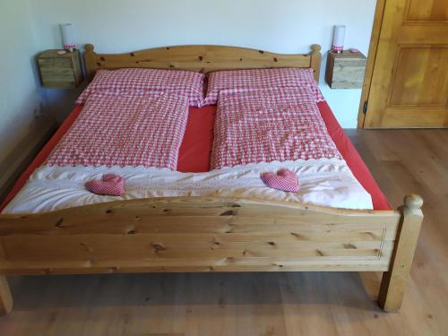 uma cama de madeira com dois corações cor-de-rosa em Apartment Bühlmann em Spiez