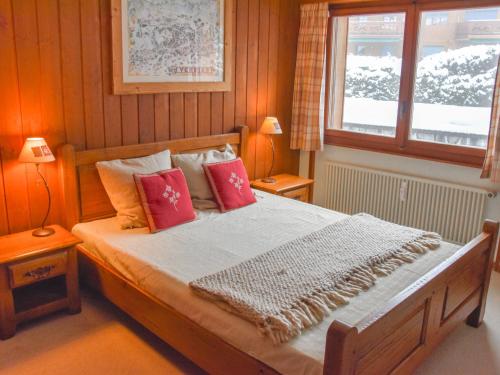 Schlafzimmer mit einem Bett mit roten Kissen und einem Fenster in der Unterkunft Apartment Mondzeu b260 by Interhome in Verbier