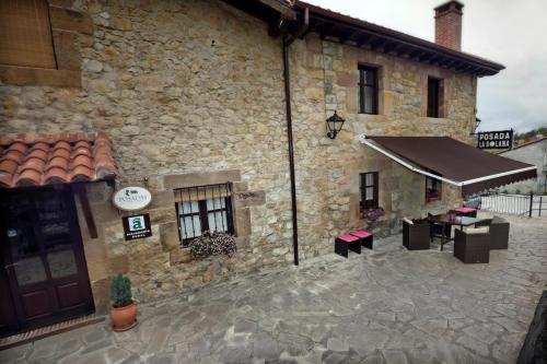 a building with a patio with tables and awning at Posada La Solana - Adults Only in Santillana del Mar