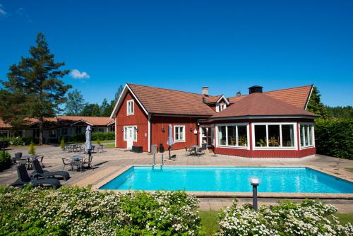 a house with a swimming pool in front of a house at Hotell Miskarp in Mjölby