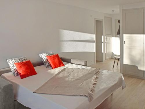 uma cama branca com almofadas vermelhas num quarto em Studio Diure 0113 by Interhome em Verbier
