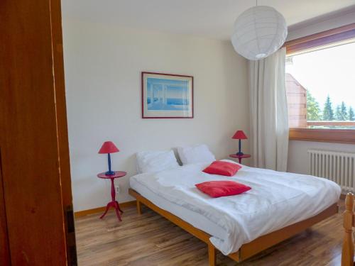 1 dormitorio con 1 cama con 2 almohadas rojas en Apartment Bruyères A32 by Interhome, en Verbier
