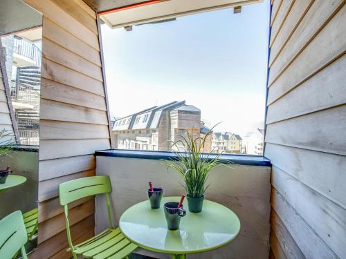 d'une petite table et de chaises sur un balcon avec fenêtre. dans l'établissement Studio Les Marinas-9 by Interhome, à Deauville
