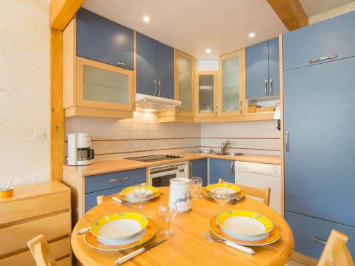 une cuisine avec une table en bois et des armoires bleues dans l'établissement Apartment Le Curling B - Val Claret-37 by Interhome, à Tignes