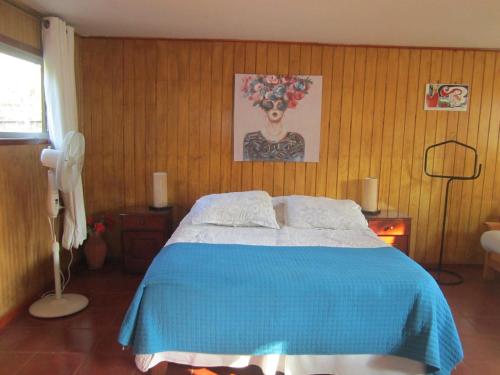 a bedroom with a bed with a blue blanket at Cabaña Cerezo in Guayacán