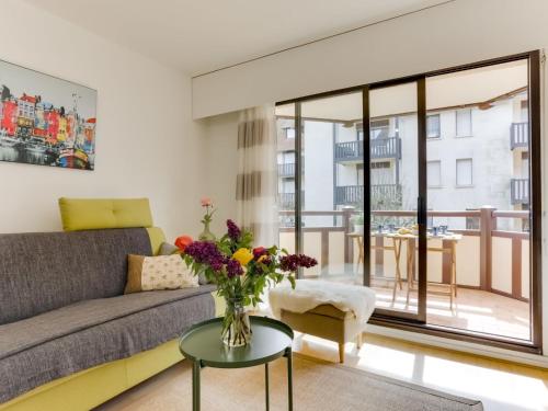 sala de estar con sofá y mesa con un jarrón de flores en Apartment Le Fairway-6 by Interhome, en Deauville