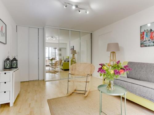 a living room with a couch and a table with flowers at Apartment Le Fairway-6 by Interhome in Deauville