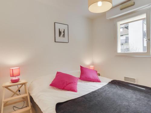 a bedroom with a bed with pink pillows and a window at Apartment Le Fairway-6 by Interhome in Deauville