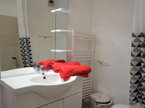 a bathroom with a white sink and red towels at Studio Le Parc de la Chaumière-5 by Interhome in Trouville-sur-Mer