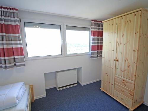 a bedroom with a bed and two windows at Apartment Eifelnatur - Haus 3-2 by Interhome in Immerath