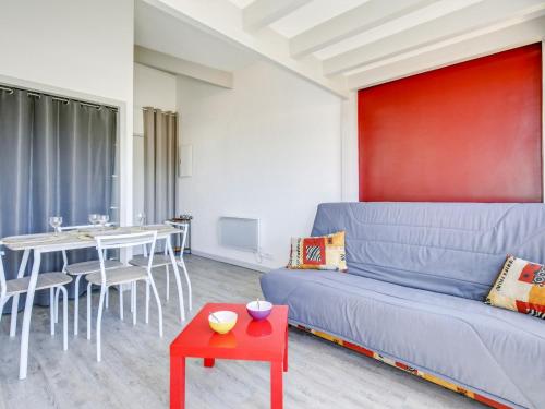 een woonkamer met een blauwe bank en een tafel bij Studio La Passerelle by Interhome in Gujan-Mestras