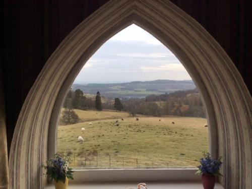 an arch window with a view of a field at Holiday Home Wester Riechip by Interhome in Dunkeld