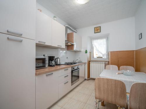 uma cozinha com armários brancos e uma mesa com cadeiras em Apartment Bumbak by Interhome em Umag