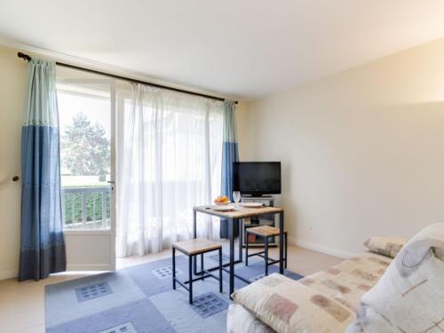 Cette chambre comprend un lit et un bureau avec une télévision. dans l'établissement Studio Les Prairies by Interhome, à Deauville