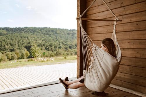 a woman sitting in a hammock on a porch at Sielska Chyża in Rzepedż