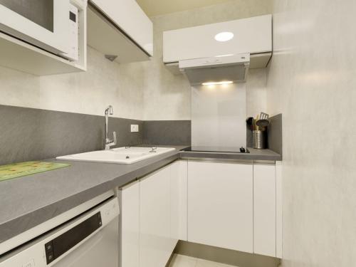 une cuisine avec des armoires blanches et un évier dans l'établissement Apartment Les Jardins du Port-8 by Interhome, au Grau-du-Roi
