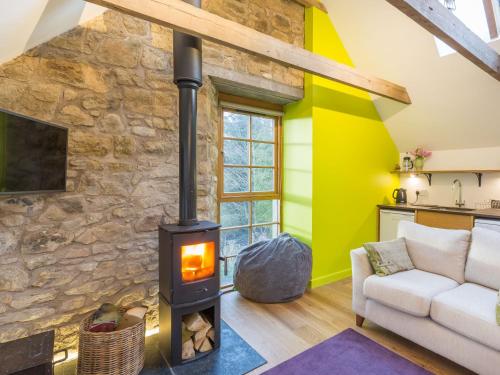 a living room with a stone wall and a wood stove at Holiday Home The Hayloft by Interhome in Edinburgh