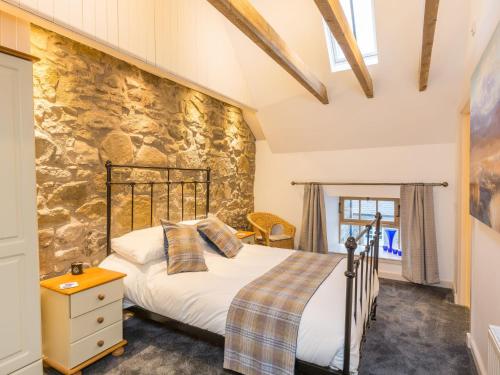 een slaapkamer met een bed en een stenen muur bij Holiday Home The Hayloft by Interhome in Edinburgh