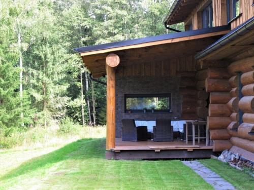 une cabane en rondins avec une table et des chaises sur la terrasse couverte dans l'établissement Chalet Srub Kuří by Interhome, à Benešov nad Černou