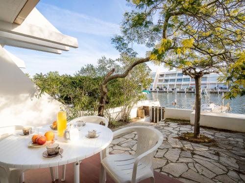 - une table et des chaises blanches sur une terrasse avec eau dans l'établissement Apartment Les Marinas de la Plage II by Interhome, au Grau-du-Roi
