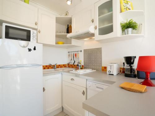 - une cuisine blanche avec des placards blancs et une chaise rouge dans l'établissement Apartment Le Grand Galion-2 by Interhome, au Grau-du-Roi