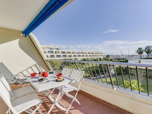 a balcony with a table and chairs with a view of the ocean at Apartment Les Jardins du Port-10 by Interhome in Le Grau-du-Roi