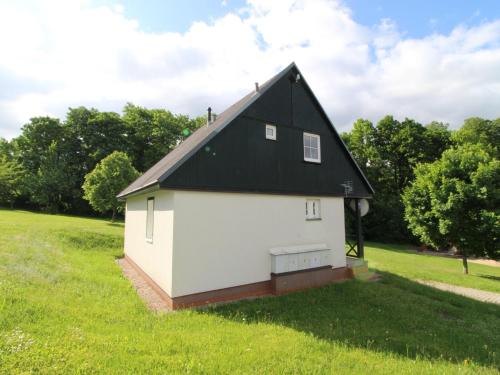 a white barn with a black roof in a field at Holiday Home Holiday Hill 36 by Interhome in Lauterwasser
