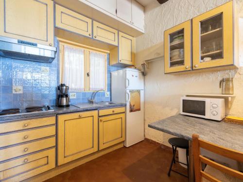 a kitchen with yellow cabinets and a white refrigerator at Apartment Village de Silhouette-5 by Interhome in Grimaud