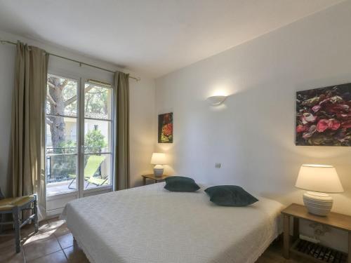 ein Schlafzimmer mit einem Bett mit zwei Kissen und einem Fenster in der Unterkunft Apartment Le Jardin d'Artemis-2 by Interhome in Saint-Tropez