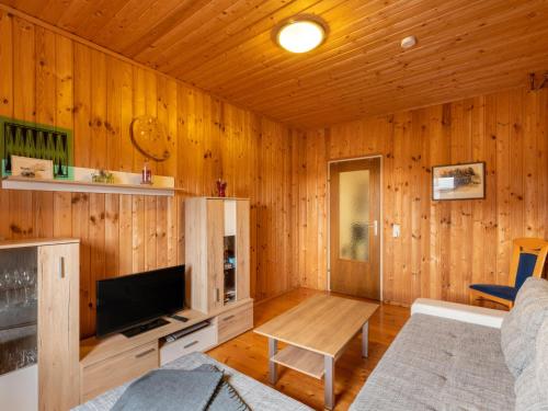 a living room with wood paneled walls and a television at Holiday Home Pistenblick-4 by Interhome in Hochrindl