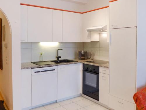 a white kitchen with white cabinets and a sink at Apartment Alpes et Lac 28 by Interhome in Champex