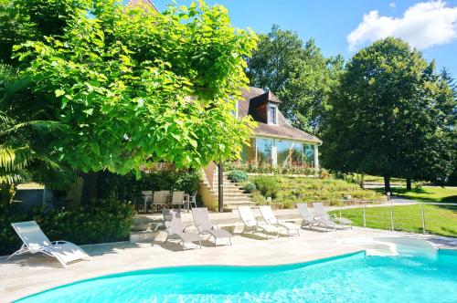 uma piscina com espreguiçadeiras e uma casa em Les Feuillantines Perigord Noir em Saint-Cyprien