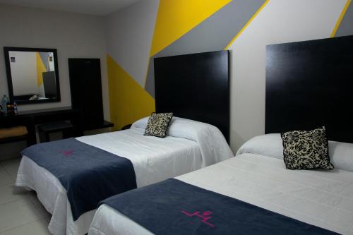 a hotel room with two beds and a mirror at Hotel HAUS Express in Orizaba