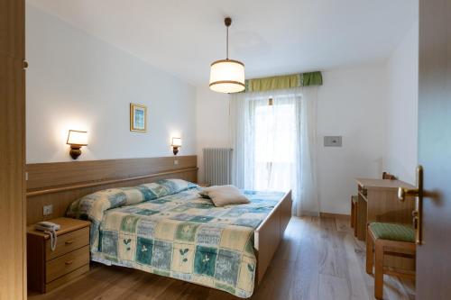 a bedroom with a bed and a desk and a window at Latemar - Hotel Suites Spa in Soraga