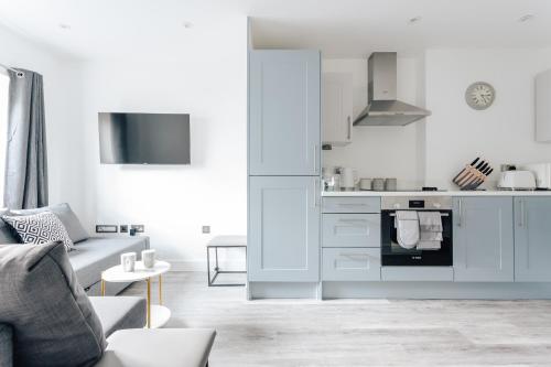 a white living room with a couch and a kitchen at Contemporary Two Bedroom Duplex - Secluded Residence with Parking in a Prime Central Location in Bournemouth