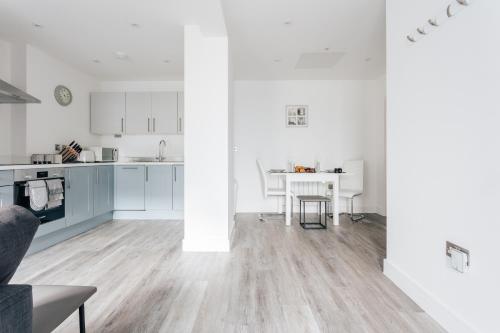 a kitchen and living room with white cabinets and a table at Contemporary Two Bedroom Duplex - Secluded Residence with Parking in a Prime Central Location in Bournemouth