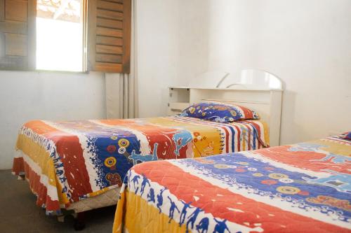 a room with three beds with colorful blankets at Casa perto da Praia Canto da Barra em Fortim CE in Fortim