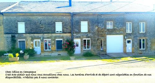 un antiguo edificio de ladrillo con dos puertas blancas de garaje en CHEZ CELINE en campagne, en Mazerny