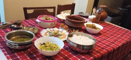a table with bowls of food on a red checked table cloth at NIDHIVANA FARMS & RESORT, bakrebail-salethoor rd, Mangalore in Mangalore