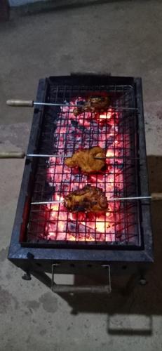 a grill with two fried chickens cooking on it at NIDHIVANA FARMS & RESORT, bakrebail-salethoor rd, Mangalore in Mangalore