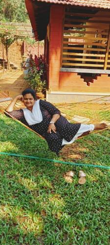 a woman laying on the grass in front of a house at NIDHIVANA FARMS & RESORT, bakrebail-salethoor rd, Mangalore in Mangalore