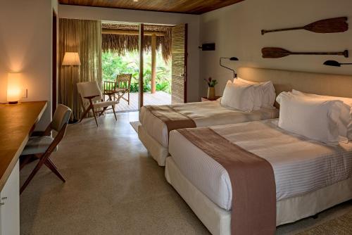 a hotel room with two beds and a desk and chairs at Hotel Fasano Trancoso in Trancoso