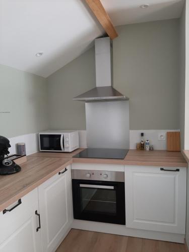 une cuisine avec des armoires blanches et un four à plaques de cuisson dans l'établissement La petite Vineuilloise 10min de Châteauroux 40min zoo de Beauval, à Vineuil