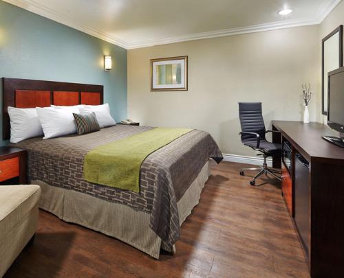 a hotel room with a bed and a desk at American Inn Downey in Downey