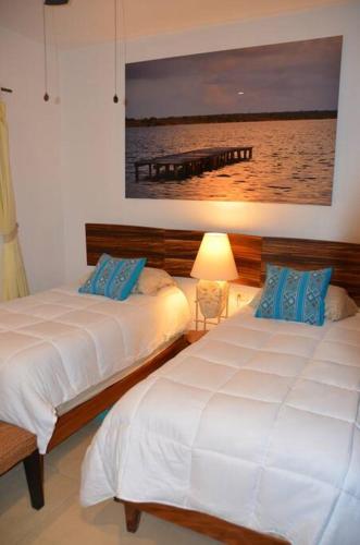 two beds in a bedroom with a picture on the wall at Beautiful condo with pool in Tulum