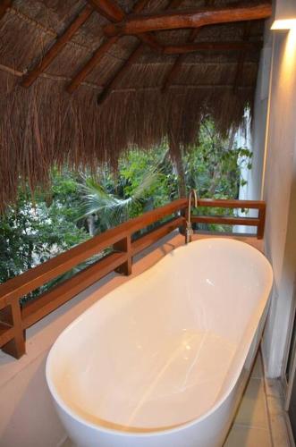 a white bath tub in a room with a window at Beautiful condo with pool in Tulum