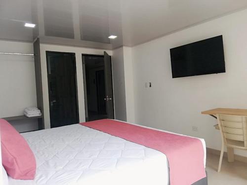 a bedroom with a bed and a television on the wall at Hotel Monarka-Edificio in Popayan